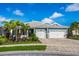 Charming blue home with a three-car garage, brick driveway, manicured lawn, and beautiful landscaping at 5533 Long Shore Loop, Sarasota, FL 34238