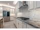 Well-lit kitchen features stainless appliances, stone counters, white cabinets, and modern exhaust hood at 5533 Long Shore Loop, Sarasota, FL 34238