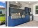 Built-in outdoor kitchen with stainless steel grill, backsplash, and sleek blue cabinets for stylish entertaining at 5533 Long Shore Loop, Sarasota, FL 34238