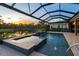 Relaxing screened pool with a spa and water feature overlooking a tranquil pond at sunset at 5533 Long Shore Loop, Sarasota, FL 34238