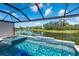 Swimming pool and spa overlooking the lake, surrounded by lush greenery and covered by a black screen enclosure at 5533 Long Shore Loop, Sarasota, FL 34238