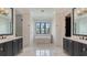 Bright bathroom with double vanity, soaking tub by the window, and white marble floors at 670 Old Compass Rd, Longboat Key, FL 34228