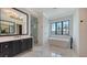 Luxury bathroom with dual sink vanity, soaking tub, glass shower, and elegant lighting at 670 Old Compass Rd, Longboat Key, FL 34228
