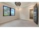 Bright bedroom features a large window, an elegant light fixture, and access to an ensuite bathroom at 670 Old Compass Rd, Longboat Key, FL 34228