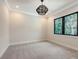 Bedroom features a modern light fixture, plush carpet, neutral walls, and views of the tropical landscape at 670 Old Compass Rd, Longboat Key, FL 34228