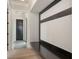 Modern hallway with unique wall detail, bench, light wood floors, and dark door at 670 Old Compass Rd, Longboat Key, FL 34228