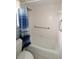 A white tiled shower and tub combo, with a blue striped shower curtain, and chrome handle bars for assistance at 753 Tropical Cir, Sarasota, FL 34242