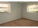 This is a vacant bedroom with two windows, a ceiling fan, and neutral-colored walls and carpet at 753 Tropical Cir, Sarasota, FL 34242
