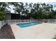Backyard pool surrounded by white fencing, lush foliage, and a screen porch on the rear of the house at 753 Tropical Cir, Sarasota, FL 34242