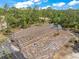 Aerial view of a construction site featuring a large greenhouse frame with equipment nearby amid trees at 8146 Tropicaire Blvd, North Port, FL 34291