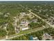 Expansive aerial view of lush acreage featuring numerous structures and greenhouses amidst verdant landscape at 8146 Tropicaire Blvd, North Port, FL 34291