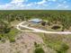 Secluded property with a modern house, long driveway, and private pond nestled within a dense forest landscape at 8146 Tropicaire Blvd, North Port, FL 34291