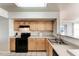 A cozy kitchen featuring a stainless steel sink, black appliances, and light wood cabinets set on a neutral tile floor at 1030 Villagio Cir # 103, Sarasota, FL 34237