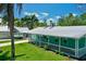 The home features a metal roof, a white railing and lush tropical foliage at 12107 45Th W Ave, Cortez, FL 34215