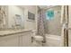 Well-lit bathroom with granite vanity, bathtub with shower, patterned curtain, and neutral tile flooring at 1530 Pine Bay Dr, Sarasota, FL 34231