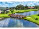 Picturesque view of wooden bridge that goes over the lake, surrounded by lush green grass and tropical palm trees at 1613 Gondola Park Dr # 1613, Venice, FL 34292