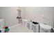 Bright laundry room with white tile floors, multiple laundry baskets, and cleaning supplies at 16418 Slate Pl, Lakewood Ranch, FL 34211