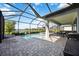 Enclosed pool area featuring stone pavers, relaxing lounge area, and lake views beyond the screen enclosure at 16418 Slate Pl, Lakewood Ranch, FL 34211