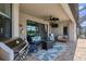 Covered patio area with BBQ grill, seating area, ceiling fan and view into the home's living room at 17850 Polo Trl, Bradenton, FL 34211