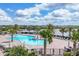 Beautiful community pool surrounded by palm trees and lounge chairs overlooking a serene lake at 17850 Polo Trl, Bradenton, FL 34211