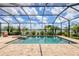 Screened-in pool area with a spa, lake view, lush landscaping, and patio at 17850 Polo Trl, Bradenton, FL 34211