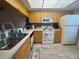 Well-lit kitchen featuring a double sink, bright cabinets, and essential appliances at 1999 Kings Hwy # 26A, Punta Gorda, FL 33980