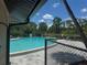 Inviting community pool surrounded by a fence, lush greenery and palm trees under a clear blue sky at 1999 Kings Hwy # 26A, Punta Gorda, FL 33980