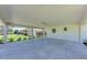 Open carport space showing the concrete flooring and providing covered parking with outdoor views at 2400 Lake Shore Dr, Nokomis, FL 34275