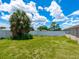 Backyard featuring a grassy lawn, surrounded by a white fence and mature trees at 2416 Emory Ave, Bradenton, FL 34207