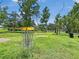 A disc golf basket sits in a grassy field, surrounded by trees, with blue skies overhead at 245 Cape Harbour Loop # 103, Bradenton, FL 34212