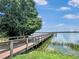 A wooden dock extends out into a serene lake, framed by a lush green tree at 245 Cape Harbour Loop # 103, Bradenton, FL 34212