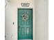Close-up of a teal front door adorned with a welcome wreath, creating a warm and inviting entrance at 245 Cape Harbour Loop # 103, Bradenton, FL 34212