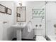 Elegant half bath features a pedestal sink, decorative mirror, and glass shelving at 2748 Orchid Oaks Dr # 202, Sarasota, FL 34239