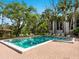 Inviting community pool surrounded by lush trees, lounge chairs, and a gazebo at 2748 Orchid Oaks Dr # 202, Sarasota, FL 34239