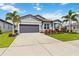 Charming single-story home with a manicured lawn, palm trees, and a gray two car garage at 3602 Quiet Dr, Sarasota, FL 34240