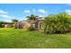 Landscaped backyard featuring a screened-in patio, lush lawn, and tropical palm trees under a sunny sky at 408 166Th E St, Bradenton, FL 34212