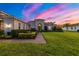 Lovely single-story home featuring manicured landscaping, a brick walkway, and a beautiful sunset at 408 166Th E St, Bradenton, FL 34212
