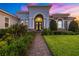 Inviting single-story home showcasing lush tropical landscaping, decorative entryway, and brick walkway at 408 166Th E St, Bradenton, FL 34212