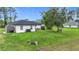 Spacious backyard with lush lawn, mature tree, seating, and a view of the home's exterior at 4148 Lobelia St, North Port, FL 34286