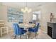Charming dining room with blue velvet chairs, modern lighting, and a glimpse into the updated kitchen at 4214 Groveland Ave, Sarasota, FL 34231