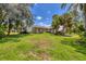 View of the home's exterior and spacious backyard with lush trees and a Wildwood trailer parked on the side at 4357 Mermell Cir, North Port, FL 34291
