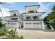 Modern three-story home showcasing balconies, a three-car garage, and a brick driveway at 455 Cleveland Dr, Sarasota, FL 34236