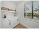 Clean laundry room featuring a sink, storage cabinets, and a bright window with a view at 455 Cleveland Dr, Sarasota, FL 34236