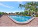 Community pool area with brick decking, lounge chairs, lush landscaping, and a lake view at 495 Oak Hill Cir # 44, Sarasota, FL 34232