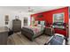 A bedroom with hardwood floors and a red accent wall with a bed and a treadmill at 5301 Shell Mound Cir, Punta Gorda, FL 33982