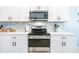 Modern kitchen boasts stainless steel appliances, white cabinetry, and a stylish backsplash for a contemporary feel at 5301 Shell Mound Cir, Punta Gorda, FL 33982
