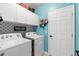 A bright laundry room with front-loading washer and dryer, white cabinets, and aqua walls at 5301 Shell Mound Cir, Punta Gorda, FL 33982