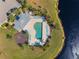 Aerial view of the community pool with plenty of lounge chairs, lush landscaping, and a tranquil lake view at 5301 Shell Mound Cir, Punta Gorda, FL 33982