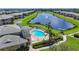 Scenic aerial view of clubhouse, pool, lake with fountains, and surrounding residential community at 6604 7Th Avenue W Cir, Bradenton, FL 34209