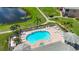 Aerial view of a private pool and lounge area beside a pond and grassy walking path at 6604 7Th Avenue W Cir, Bradenton, FL 34209